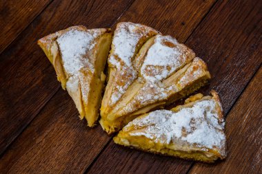 Tahtaya şeker tozu sürülmüş taze pişmiş elmalı turta. Hom