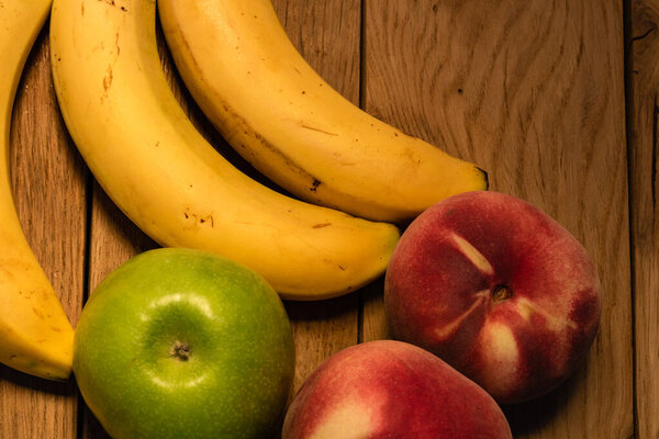 Apple, peach and bananas on a wooden board. Composition of healt