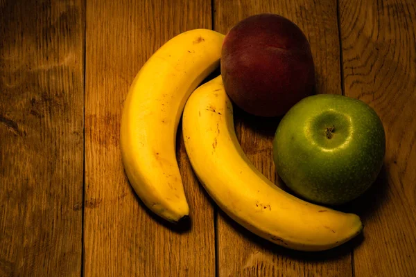 Jabłko, brzoskwinia i banany na drewnianej desce. Skład uzdrowienia — Zdjęcie stockowe