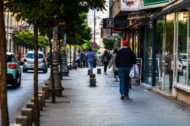 Buchare 'de Victoriei Caddesi' nin kaldırımında yürüyen genç adam.