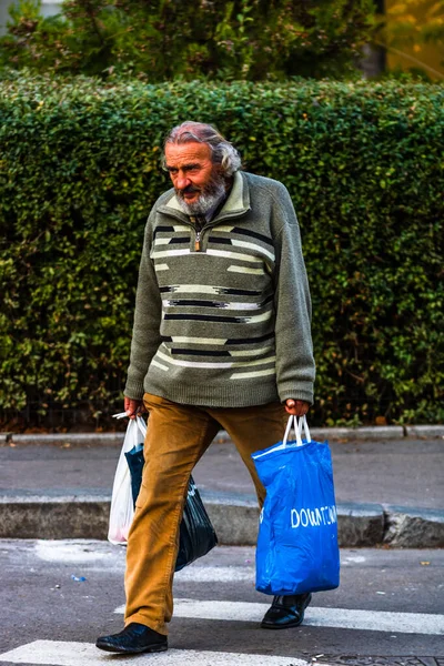 Old man crossing the street and carrying bags of groceries in Bu — Stock Photo, Image