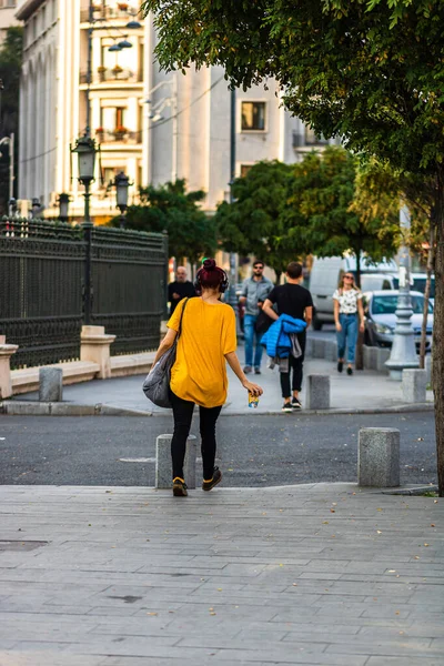 Νεαρό κορίτσι ακούει μουσική ενώ περπατά με ένα φλιτζάνι καφέ σε ο — Φωτογραφία Αρχείου