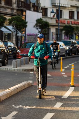 Bükreş, Rom 'da sokakta elektrikli scooter kullanan genç bir adam