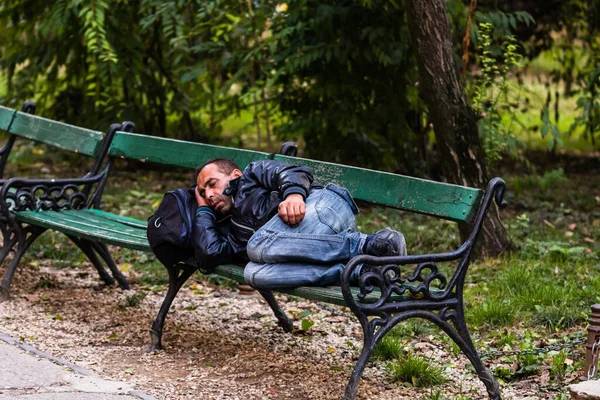 Férfi egy fa padon alszik a parkban, Bukarest, Románia, — Stock Fotó