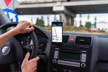 Araba gösterge panelindeki akıllı telefondaki waze haritaları uygulaması, sürücü, şehir trafiğinde doğru yolu göstermek için harita uygulaması kullanıyor. Bükreş, Romanya, 2020.