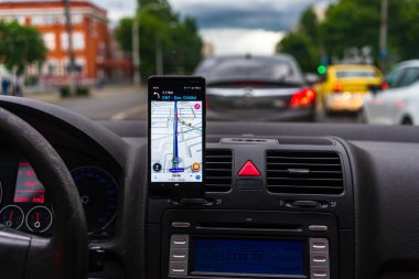 Araba gösterge panelindeki akıllı telefondaki waze haritaları uygulaması, sürücü, şehir trafiğinde doğru yolu göstermek için harita uygulaması kullanıyor. Bükreş, Romanya, 2020.