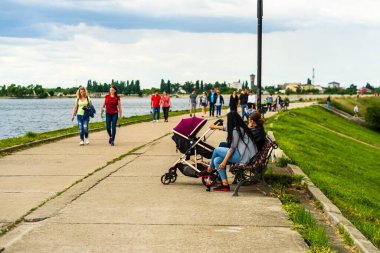 İnsanlar göl kenarındaki bir parkın sokaklarında yürüyor, dinleniyor ve eğleniyorlar. Bükreş, Romanya, 2020