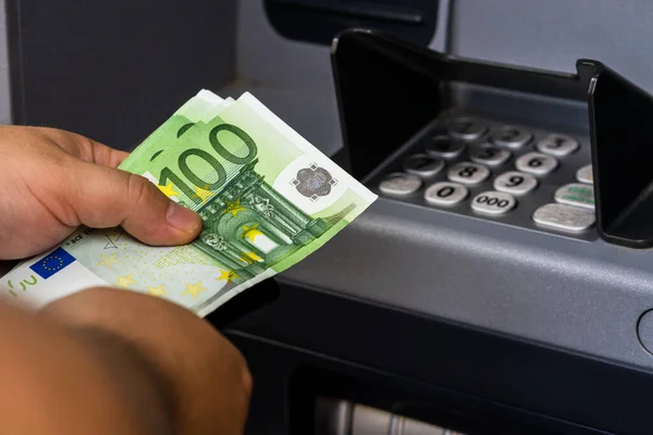 Mevduat bankamatik para makinesinden EURO 'yu çekti. ATM makinesinde EURO banknotlarını tutan adam.