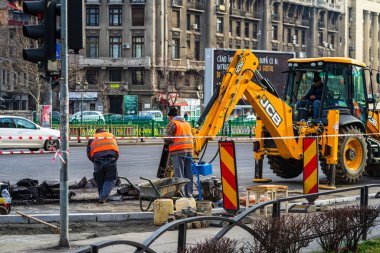 Sarı kepçe yükleyici ve inşaat alanında işçiler Bükreş, Romanya, 2020 'de çalışmaya hazır.