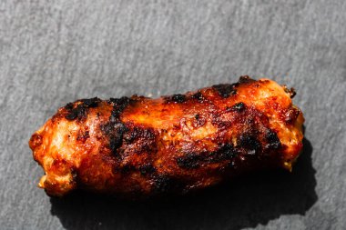 Izgara sosisi izole edilmiş küçük siyah kesme tahtasına yakın tut. Barbekü, ızgara ve yemek konsepti.