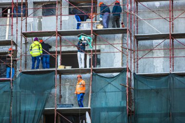 Metal iskeledeki işçiler apartmanın dış cephesini yeniliyorlar. Bükreş, Romanya, 2020