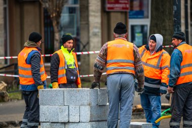 Yansıtıcı yelek giyen müteahhit işçiler sokak kaldırımlarını onarmaya hazırlanıyorlar. Bükreş, Romanya, 2020