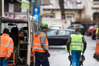 Yansıtıcı yelek giyen müteahhit işçiler sokak kaldırımlarını onarmaya hazırlanıyorlar. Bükreş, Romanya, 2020