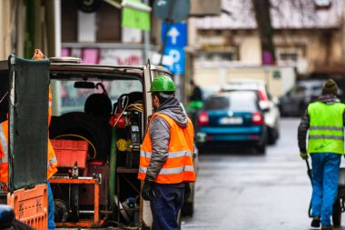 Yansıtıcı yelek giyen müteahhit işçiler sokak kaldırımlarını onarmaya hazırlanıyorlar. Bükreş, Romanya, 2020