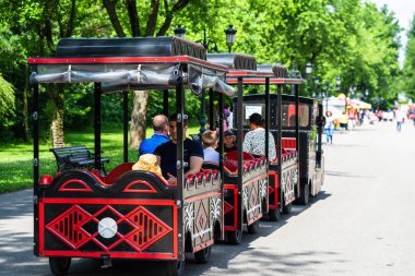 Çocuklu aileler parkta trenle geziyorlar. 2020 yılında Romanya 'nın Bükreş kentindeki Mogosoaia kentinden insanlar park ve bahçelerde yürüyor, dinleniyor ve eğleniyorlar..