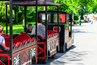 Çocuklu aileler parkta trenle geziyorlar. 2020 yılında Romanya 'nın Bükreş kentindeki Mogosoaia kentinden insanlar park ve bahçelerde yürüyor, dinleniyor ve eğleniyorlar..