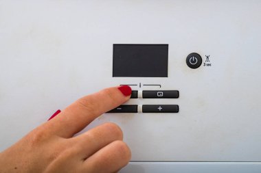 Kadın eli odadaki merkezi ısıtıcıyı kapatmaya çalışıyor. Kadın eller merkezi ısıtma kontrol panelinde. Kız el ısıtma sistemine ısı ayarlama.