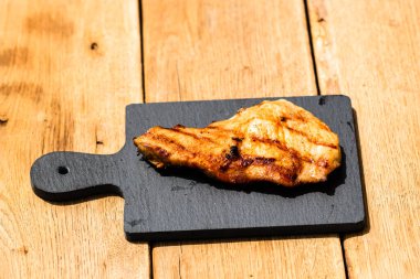 Izgara bifteği, izole edilmiş küçük siyah kesme tahtasına yakın tut. Barbekü, ızgara ve yemek konsepti.