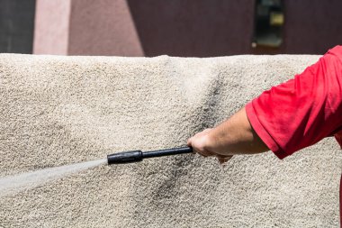 Yüksek basınçlı çamaşır makinesiyle halıları yıkayın. Yüksek basınçlı suyu yıkamak için halıyı silahla temizlemek. Ev temizliği kavramı.