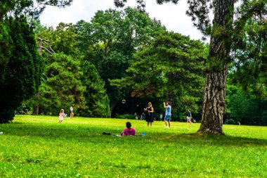 Annesi küçük kızı için sabun köpükleri yapıyor, insanlar piknik yapıyor ve parkta Coronavirus krizi sırasında eğleniyorlar ve Romanya 'nın Bükreş kentindeki Mogosoaia bölgesinin bahçeleri, 2020.