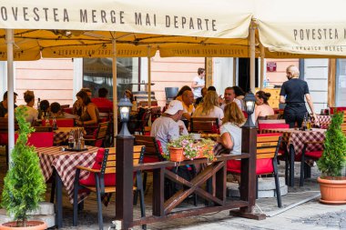 İnsanlar Coronavirus krizi sırasında Sibiu 'nun eski kasabasının sokaklarındaki yerel restoranlarda dolaşıp yemek yiyorlar. Sibiu, Romanya, 2020.