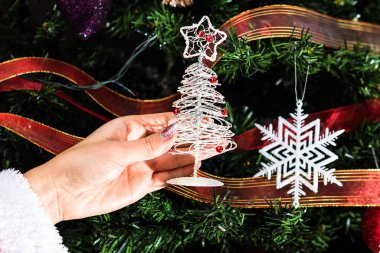 Hsnd Noel ağacının önünde küçük bir Noel ağacı heykeli tutuyor..