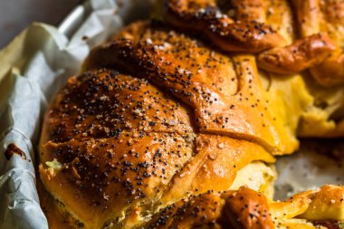 Örülmüş poğaça üzerine tuz ve haşhaş tohumlarının detaylarına odaklanmış seçici bir fotoğrafla kapat..