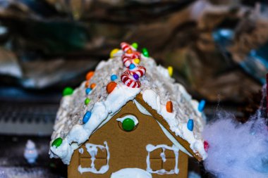 Renkli zencefilli kurabiye evi, bulanık arka planda, Noel süslemesiyle izole edilmiş..