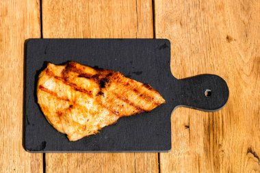 Izgara bifteği, izole edilmiş küçük siyah kesme tahtasına yakın tut. Barbekü, ızgara ve yemek konsepti.