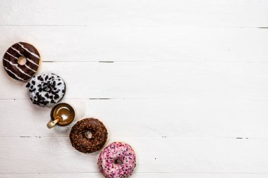 Beyaz ahşap masada renkli çörekler. Şekerli, şekerli, şekerli, şekerli, şekerli. Kopyalama alanı olan üst görünüm