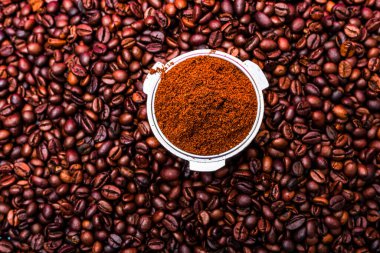 Arka planda portafilter kahve ile çevrili kavrulmuş kahve çekirdekleri.,