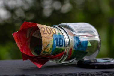 İsviçre frangı CHF banknotu cam kavanozda para biriktiriyor. Tüketim ve ekonomi. İş, bahşiş, finans, tasarruf, bankacılık ve insan kavramı