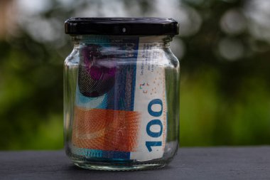 İsviçre frangı CHF banknotu cam kavanozda para biriktiriyor. Tüketim ve ekonomi. İş, bahşiş, finans, tasarruf, bankacılık ve insan kavramı