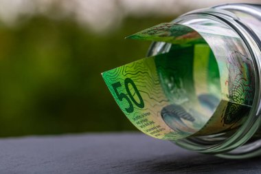İsviçre frangı CHF banknotu cam kavanozda para biriktiriyor. Tüketim ve ekonomi. İş, bahşiş, finans, tasarruf, bankacılık ve insan kavramı