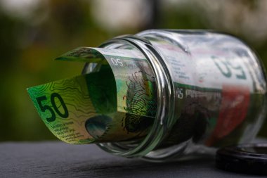 İsviçre frangı CHF banknotu cam kavanozda para biriktiriyor. Tüketim ve ekonomi. İş, bahşiş, finans, tasarruf, bankacılık ve insan kavramı