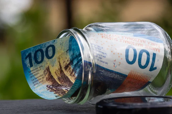 İsviçre frangı CHF banknotu cam kavanozda para biriktiriyor. Tüketim ve ekonomi. İş, bahşiş, finans, tasarruf, bankacılık ve insan kavramı