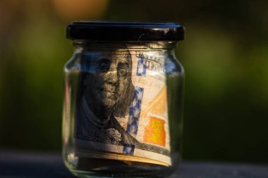 Cam kavanozda para biriktirmek için Amerikan Doları. Tüketim ve ekonomi. İş, bahşiş, finans, tasarruf, bankacılık ve insan kavramı