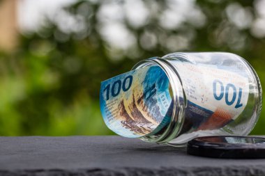 İsviçre frangı CHF banknotu cam kavanozda para biriktiriyor. Tüketim ve ekonomi. İş, bahşiş, finans, tasarruf, bankacılık ve insan kavramı