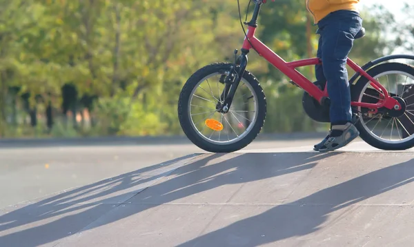 küçük çocuk bir bisiklet sporları için gider ve yamaç gün batımında güneş altında bırakarak bir skate park binmek öğrenir