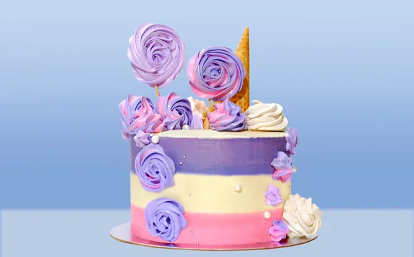 festive cake with colored stripes of pink and purple decorated with multicolored marshmallows on a blue background for decoration of holidays and birthdays