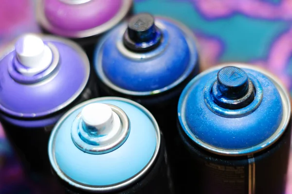 blue and violet spray cans on graffiti on an isolated white background close-up