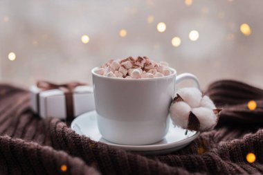 Hatmi ve hediye kutusu kahverengi şerit üzerinde sıcak örme kahverengi battaniye ile kahve fincanı.