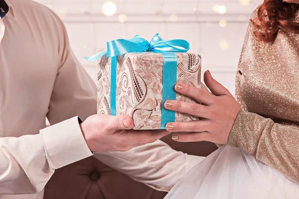 Geschenkbox mit blauem Band in den Händen eines romantischen Paares. — Stockfoto