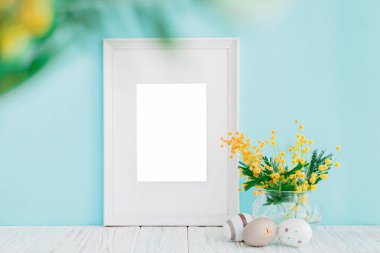 Boş beyaz ahşap çerçeve ve kopya alanı mavi zemin üzerine sarı Mimoza çiçekler. Mockup.