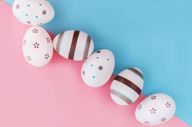 Yumurta çizgileri ve çiçek pembe ve mavi arka plan, Paskalya kavramı üzerine dekore edilmiştir. Üstten Görünüm.