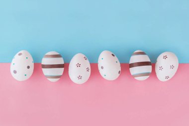 Yumurta çizgileri ve çiçek pembe ve mavi arka plan, Paskalya kavramı üzerine dekore edilmiştir. Üstten Görünüm.