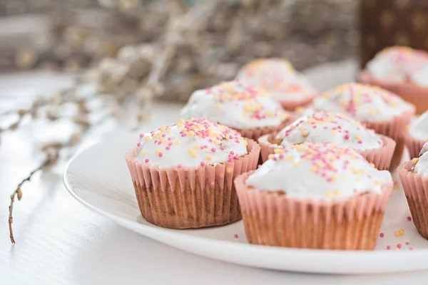 Velikonoční muffiny, koláče s cukrovinkami na bílém talíři. — Stock fotografie