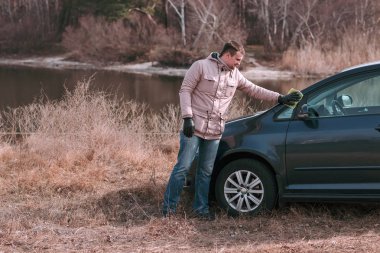 Genç yakışıklı adam sürmeden önce arabasını paçavrayla temizliyor..