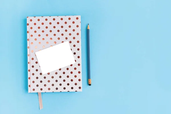 Notebook pontilhado branco, especil e pedaço de papel branco no fundo azul com espaço de cópia . — Fotografia de Stock