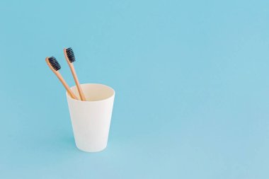 Mavi arka plan üzerinde fincan iki ahşap diş fırçası.